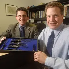 Zwei Personen sitzen an einem Tisch und präsentieren chirurgische Instrumente 