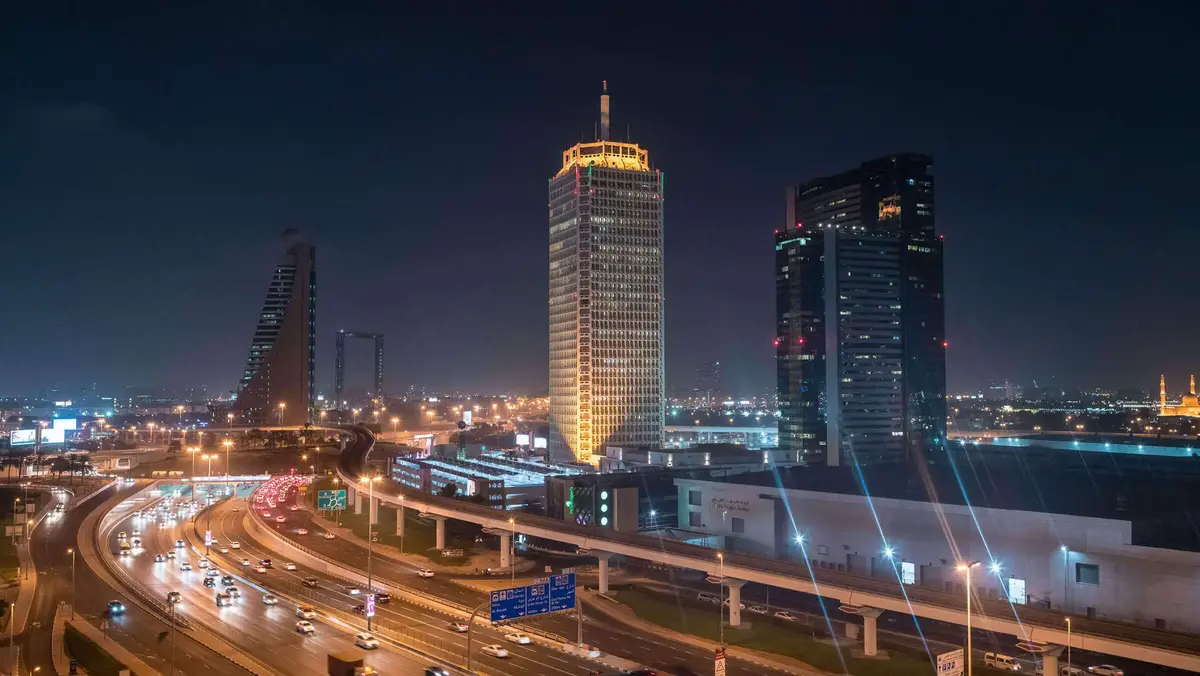 Nächtlicher Blick auf die Skyline von Dubai mit beleuchteten Hochhäusern und der Sheikh Zayed Road – modernes Stadtbild mit Verkehr und Architektur.