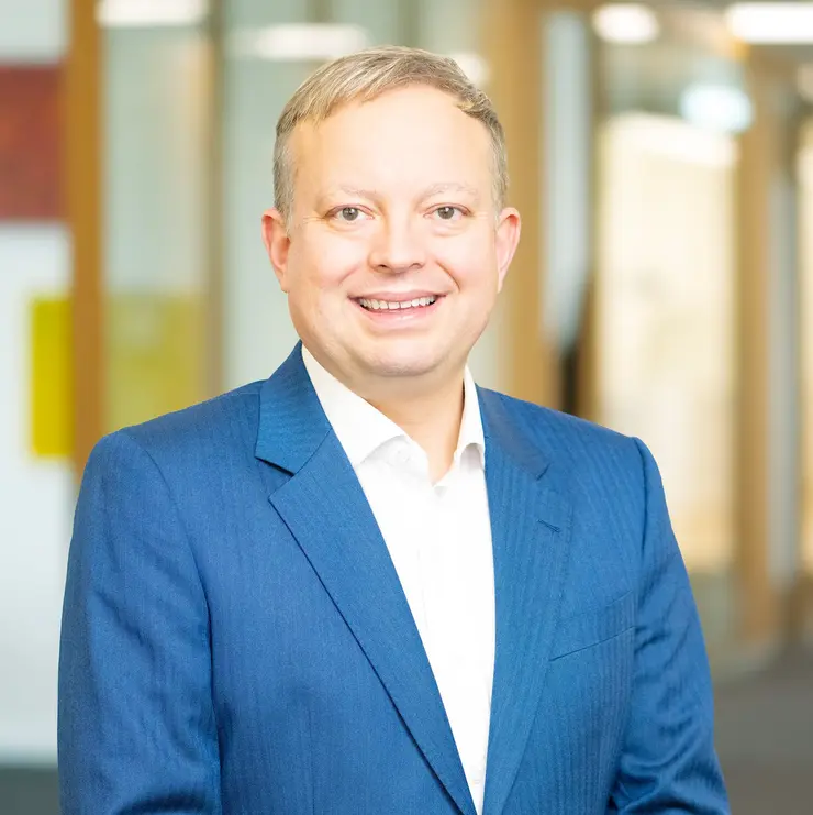 Business-Porträt eines Mannes im blauen Anzug im modernen Büroflur mit Glaswänden und Holzverkleidung 