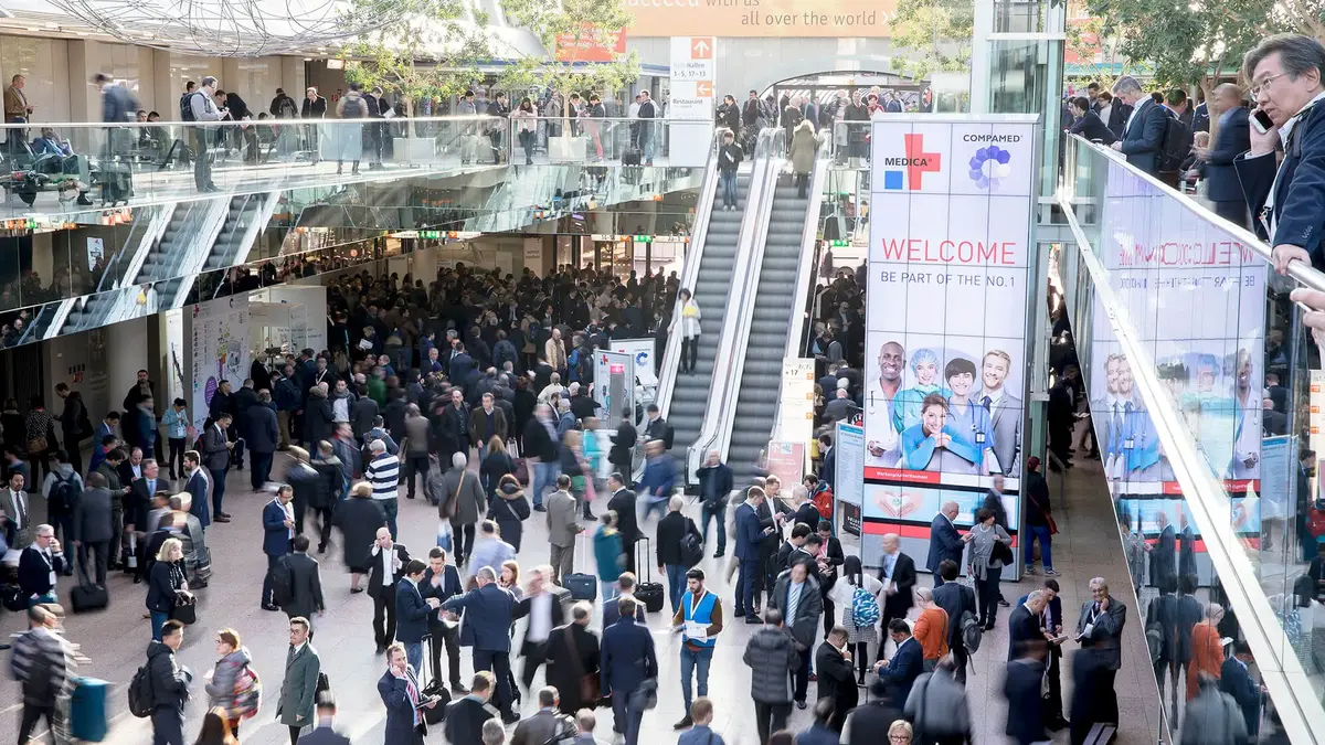 Blick in die Eingangshalle der MEDICA / COMPAMED Messe in Düsseldorf mit zahlreichen Besuchern und Ausstellern – Treffpunkt der internationalen Medizintechnikbranche.