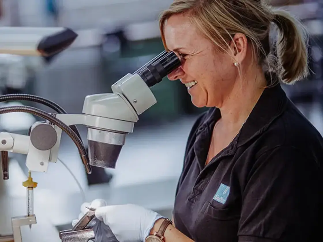 Mitarbeiterin von Sutter Medizintechnik führt unter dem Mikroskop präzise Montagearbeiten an medizinischen Instrumenten durch