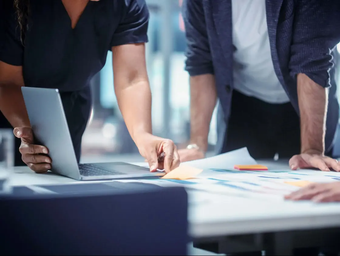 Nahaufnahme von Teammitgliedern bei der gemeinsamen Projektplanung – Strategiemeeting mit Unterlagen und Laptop