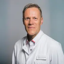 Prof. Dr. med. Steffen K. Rosahl im Arztkittel vor neutralem Hintergrund.