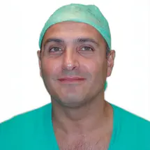 Dr. Romeo in grüner OP-Kleidung und OP-Haube vor weißem Hintergrund.