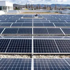 Blick auf eine großflächige Photovoltaikanlage auf dem Flachdach von Sutter Medizintechnik in Emmendingen mit sonnigem Himmel und Schwarzwaldpanorama im Hintergrund.
