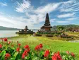 Pura Ulun Danu Temple on Lake Bratan in Bali with flowers, water, and blue sky.