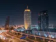 Nächtlicher Blick auf die Skyline von Dubai mit beleuchteten Hochhäusern und der Sheikh Zayed Road – modernes Stadtbild mit Verkehr und Architektur.