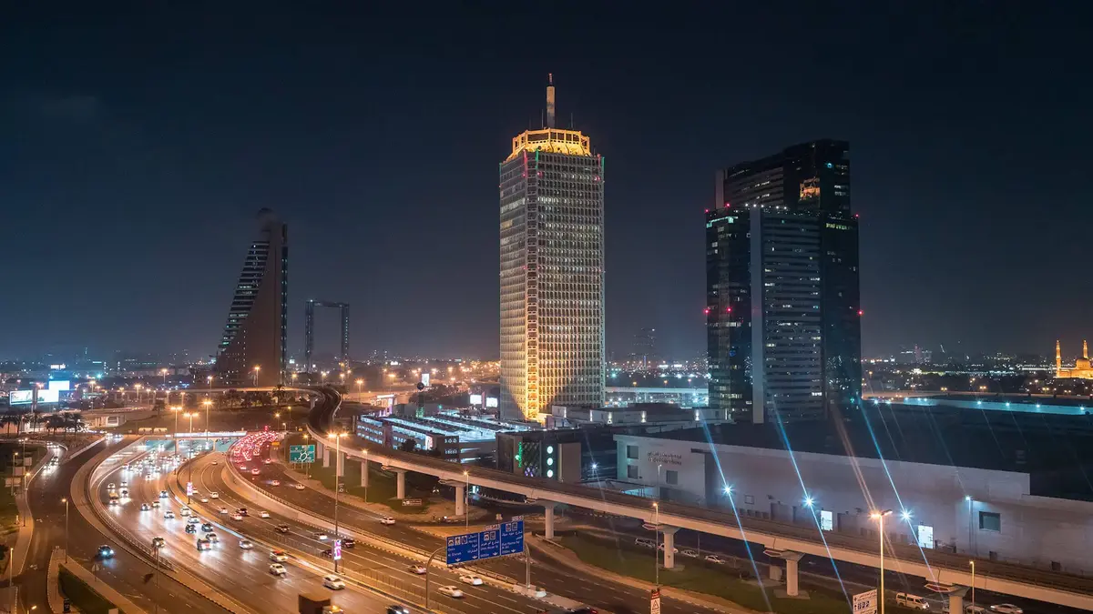 Nächtlicher Blick auf die Skyline von Dubai mit beleuchteten Hochhäusern und der Sheikh Zayed Road – modernes Stadtbild mit Verkehr und Architektur.