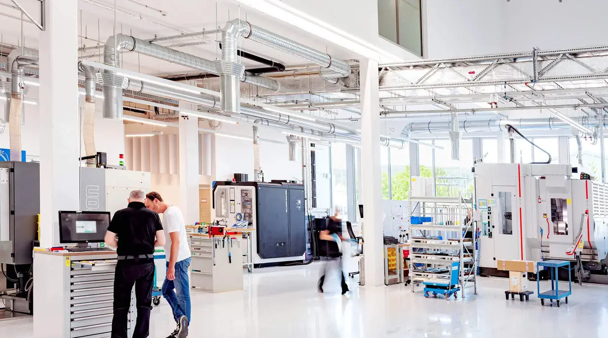 CNC-Fertigungshalle bei Sutter Medizintechnik mit modernen Maschinen, Mitarbeitenden und heller, offener Architektur.