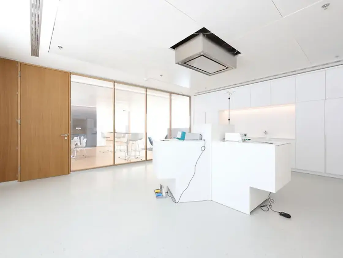 Heller Schulungsraum bei Sutter Medizintechnik mit modernem Equipment, weißen Möbeln und Glasfront zum angrenzenden Pausenbereich.