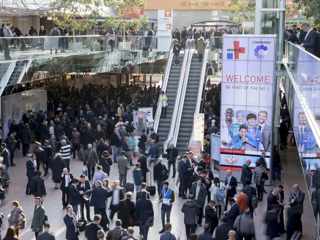 Blick in die Eingangshalle der MEDICA / COMPAMED Messe in Düsseldorf mit zahlreichen Besuchern und Ausstellern – Treffpunkt der internationalen Medizintechnikbranche.