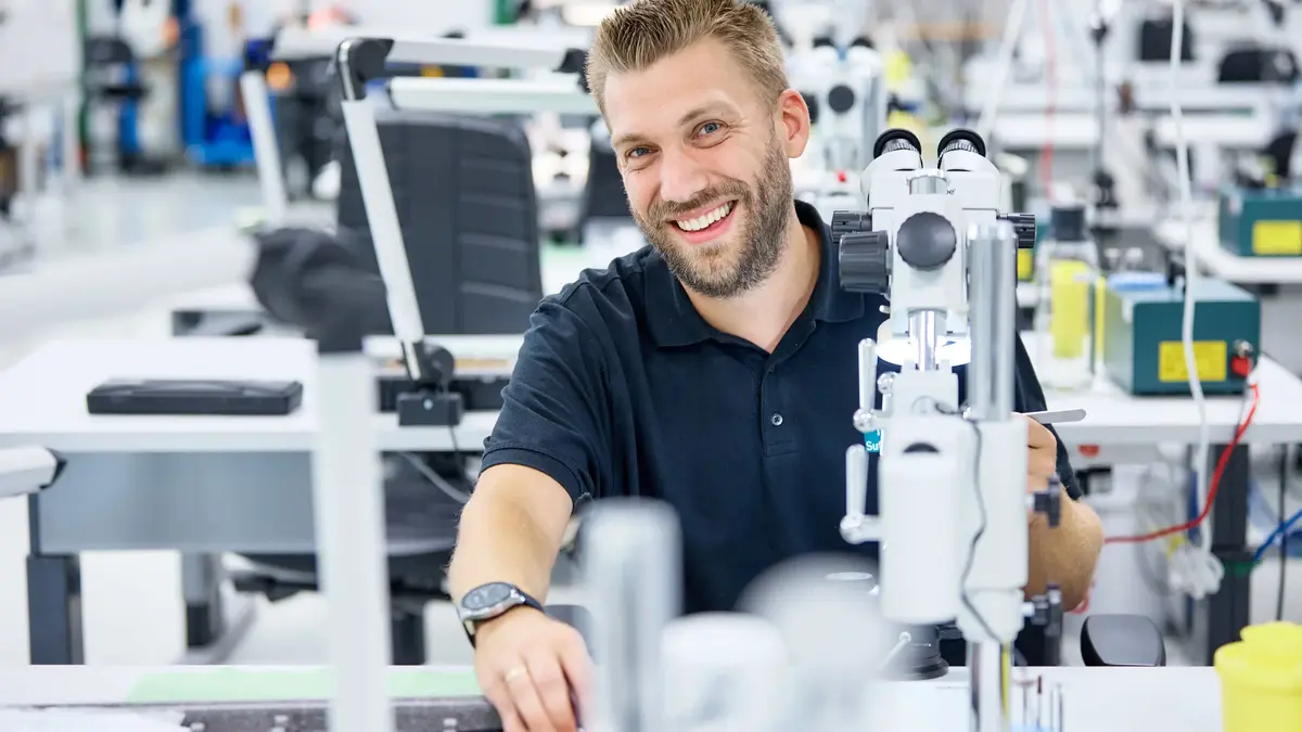 Thomas Rietsche, stellvertretender Teamleiter bei Sutter Medizintechnik, bei der Arbeit in der Feinmechanik unter dem Mikroskop – Fokus auf Qualität und Ausbildung.