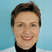 Dr. Arndt mit kurzem dunklem Haar und Hemd vor blauem Hintergrund.