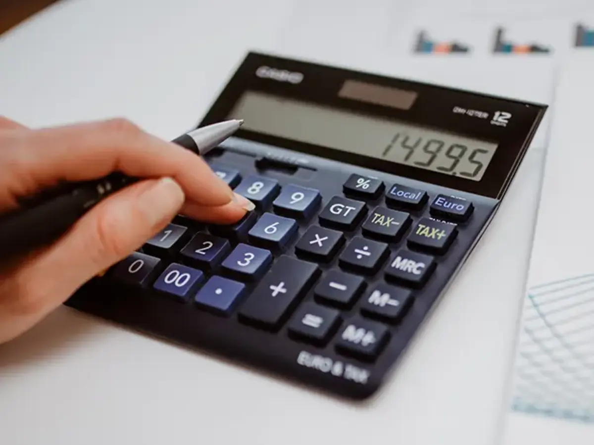 Hand mit Stift auf einem Taschenrechner – Symbolbild für die Arbeit in der Buchhaltung und Kostenkalkulation bei Sutter Medizintechnik