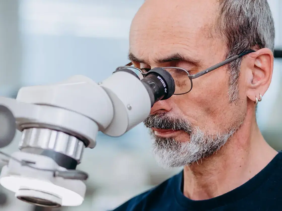 Mitarbeiter von Sutter Medizintechnik bei der Arbeit mit einem Mikroskop – Fokus auf feinmechanische Präzision in der Instrumentenfertigung