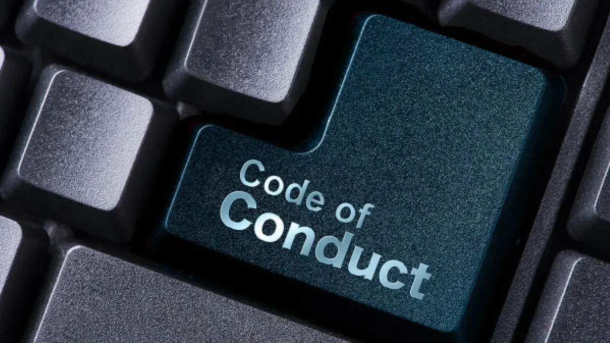 Nahaufnahme einer Computertastatur mit einer hervorgehobenen petrolfarbenen Taste, auf der „Code of Conduct“ steht.